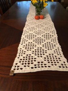 a crocheted table runner with yellow flowers in a vase on the top and bottom