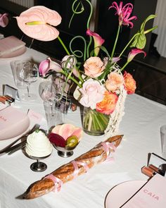 the table is set with flowers, bread and other items for an elegant dinner party