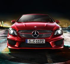 a red mercedes cla is parked in the parking lot at night with its lights on