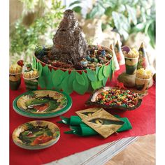 a table topped with plates and desserts covered in green paper decorations, including a tree