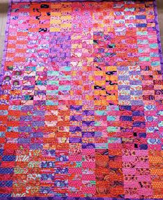 a multicolored patchwork quilt is laying on the ground