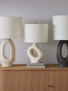 three ceramic lamps sitting on top of a wooden dresser next to a white lamp shade