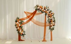 an orange and white wedding arch decorated with flowers