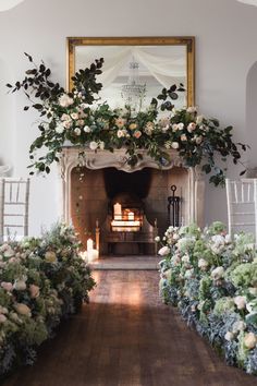 an indoor fireplace decorated with flowers and greenery