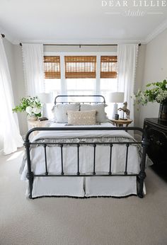 a bedroom with white bedding and black iron bedspread in front of a window