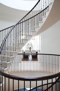 a spiral staircase in a house with white walls and black railings, leading to the second floor