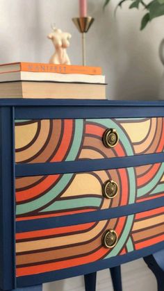 a colorful dresser with books on top and a candle in the corner next to it