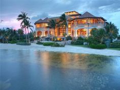 a large house sitting on top of a beach next to the ocean at night time