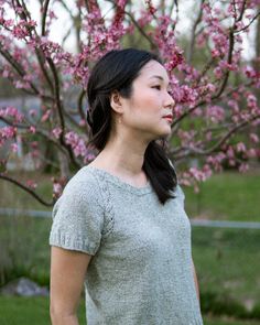 a woman standing in front of a tree with pink flowers