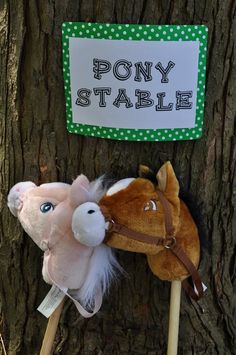 two stuffed animals on sticks attached to a tree with a sign that says pony stable