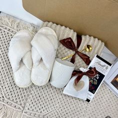 a pair of slippers sitting on top of a bed next to a cup and book