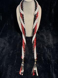 a mannequin wearing a red, white and black braided necklace on display