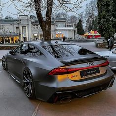 a grey sports car parked in front of a building