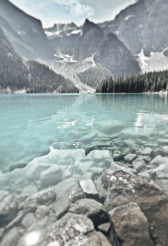 the water is crystal blue and there are mountains in the background with snow on them