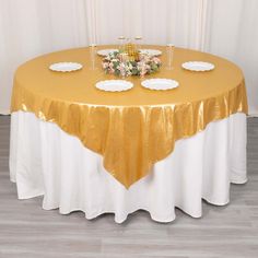 a gold and white table cloth with flowers on it is set up for a formal function