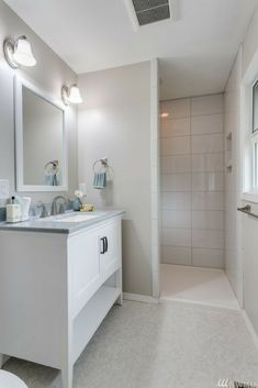 a bathroom with a sink, mirror and shower stall