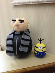 a stuffed toy sitting next to a minion on top of a table in front of a wall