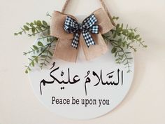 a sign hanging from the side of a wall that says peace be upon you with a bow on it