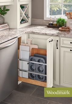 a kitchen with white cabinets and granite counter tops, an open dishwasher is in the corner