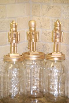 three glass jars with gold lids are sitting on a shelf next to a brick wall