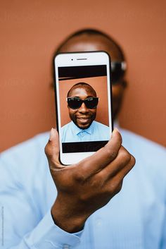 a man holding up a cell phone to take a selfie with his face on the screen