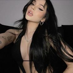 a woman with long black hair and piercings on her chest posing for the camera