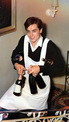 a man in an apron holding two bottles of wine