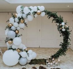 a white and gold balloon arch with greenery