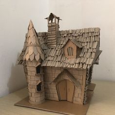 a paper model of a house with a roof made out of cardboard and two figures on top