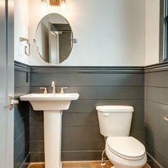 a white toilet sitting next to a sink in a bathroom under a mirror on the wall