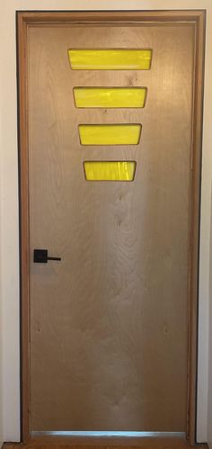 a wooden door with three yellow lights on the front and side panels, in an empty room