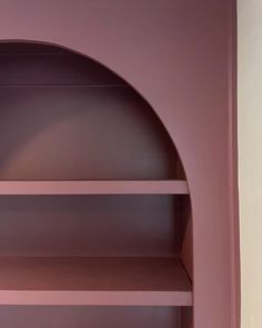 an empty shelf in the corner of a room with pink walls and shelves on each side