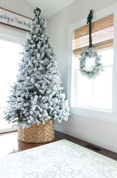 a white christmas tree in a basket next to a window