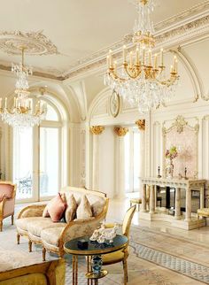 an elegant living room with chandeliers and couches