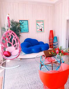 a living room filled with colorful furniture and art on the walls, including an egg chair