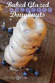 a close up of a doughnut with icing on a metal tray and blueberries in the background