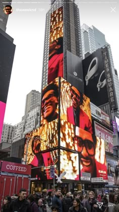 people are standing in front of a large building with billboards on it's sides