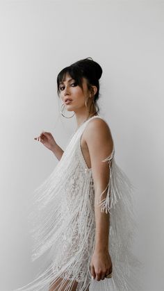 a woman wearing a white dress with feathers on it