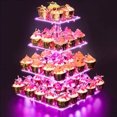 three tiered cake stand with cupcakes on it and purple lights in the background