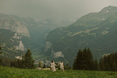 two people holding hands while walking in the mountains