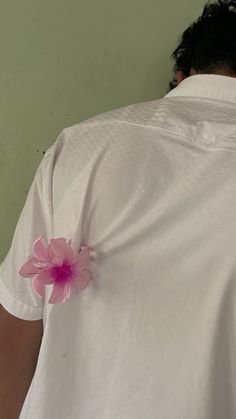 a man wearing a white shirt with a pink flower pinned to the back of his shirt