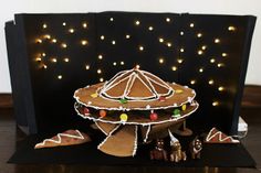 a gingerbread decorated with icing and christmas lights is displayed in front of a black card