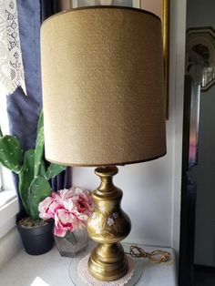 a lamp sitting on top of a table next to a potted plant and a window