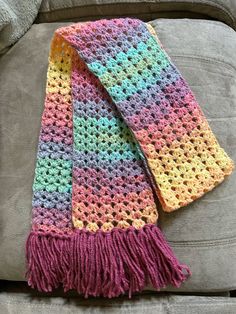 a multicolored crocheted scarf sitting on top of a couch