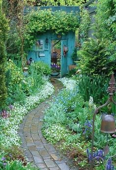 a garden with flowers, plants and a path leading to a blue door in the background