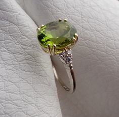 "This beautiful engagement ring is hand made in 14k yellow center and 14k white solid gold band. The natural Peridot weight is 4.02 cts and prong set in the 14k yellow gold. The Peridot measurements are 11mm x 8.9mm. The 6 side diamonds are VS-SI clarity and H color range .12cts total weight . Total gem weight is 4.14cts. We can make it any size from 5-7 and you still be able to return it within the listed time frame. Sizing outside of that range requires a resize fee if for any reason the ring Fine Jewelry Peridot Gemstones For Formal Occasions, Oval Peridot Diamond Ring For Formal Occasions, Formal Oval Peridot Diamond Ring, Formal Peridot Gemstones For May Birthstone, Luxury Oval Peridot Rings, Green Oval Diamond Ring Collectible, Luxury Hallmarked Peridot Jewelry, Elegant Peridot Gemstones For Anniversary, Elegant Peridot Gemstones As Gift