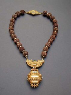 According to the seller this is a Govrishankaram - a necklace of rudraksha beads with a gold repoussé pendant and an amulet box suspended below.The Rudraksha beads are interspersed with gold rings and a repoussé gold worked pendant and clasp. Worn by a Shaivite priest only on a special ceremony. Rudraksha Necklace, Antique Gold Jewelry, India Jewelry, Ancient Jewelry, Tamil Nadu, Temple Jewellery, Traditional Jewelry