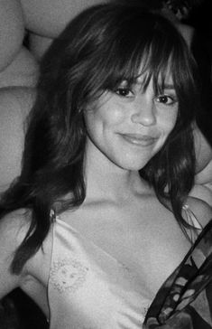 a black and white photo of a woman with long hair wearing a dress smiling at the camera