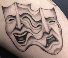 a close up of a person's arm with a tattoo on it that has two masks