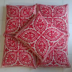 three red and white decorative pillows on a tile floor with one pillow folded up to the side